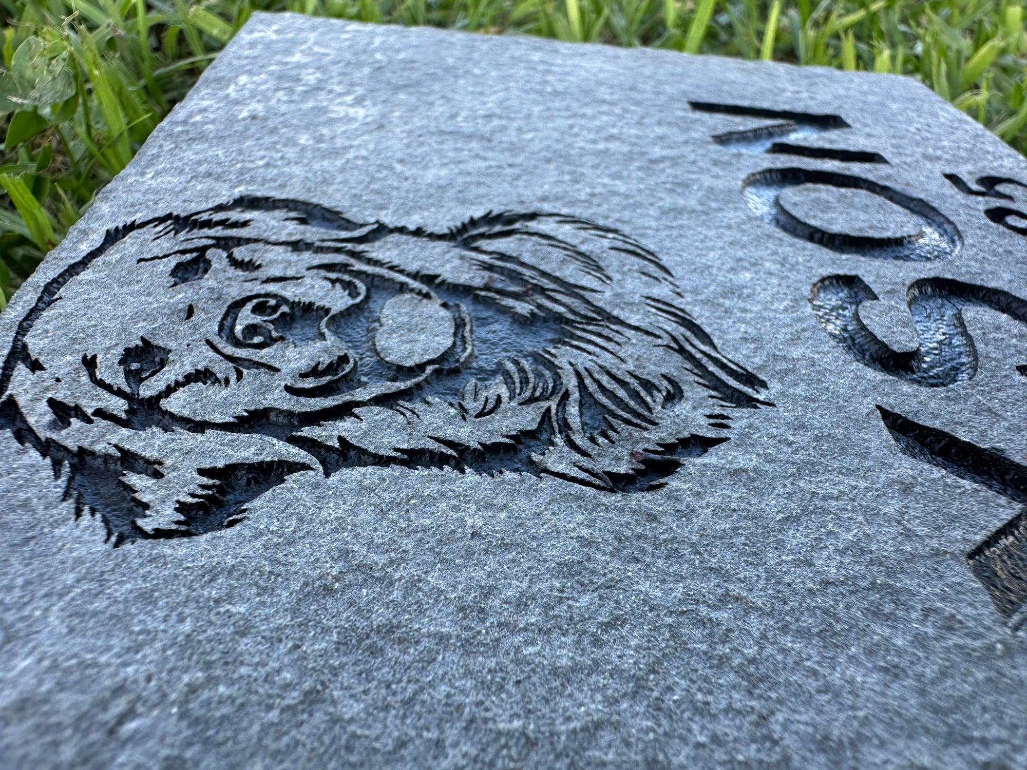 Gray stone with engraved dog portrait and text