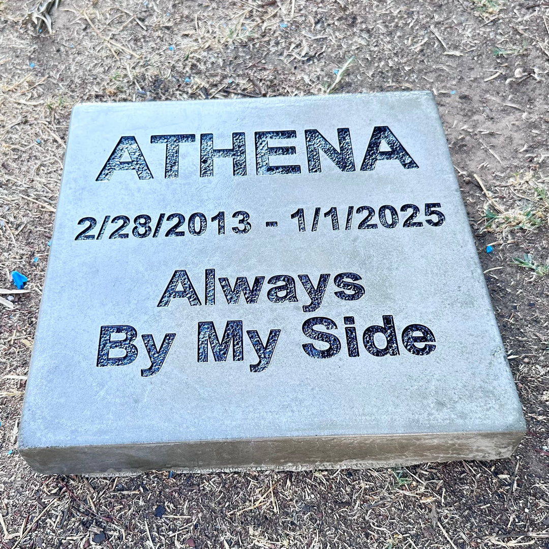 Memorial stone paver with engraved text on a grassy ground