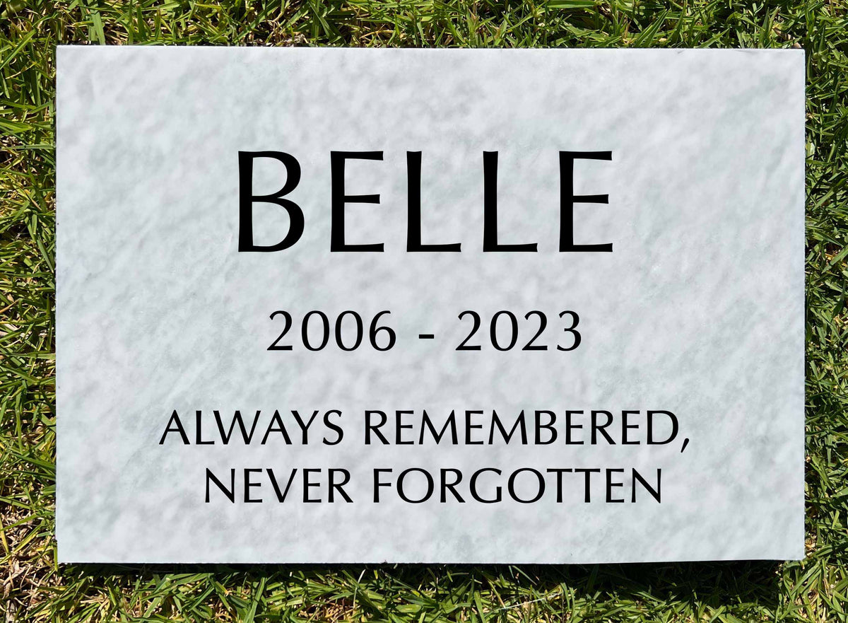 Personalized white marble pet memorial plaque displayed outdoors